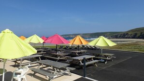 A beachside picnic area with multiple tables and colorful umbrellas.