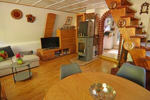 Cozy living room with a dining table, comfortable seating, flat-screen TV, and a unique spiral staircase.