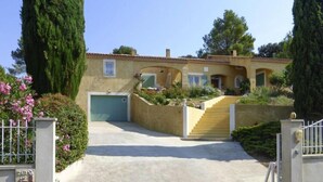 A Mediterranean-style house with a tiled roof, a front entrance with a staircase, and a garage.