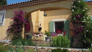 A building with a tiled roof, an archway entrance, and potted plants with flowers.