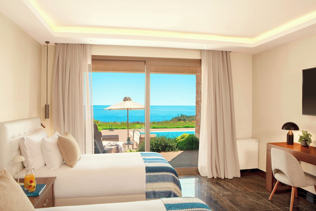 Habitación de hotel con una cama grande, un escritorio y vistas al océano.