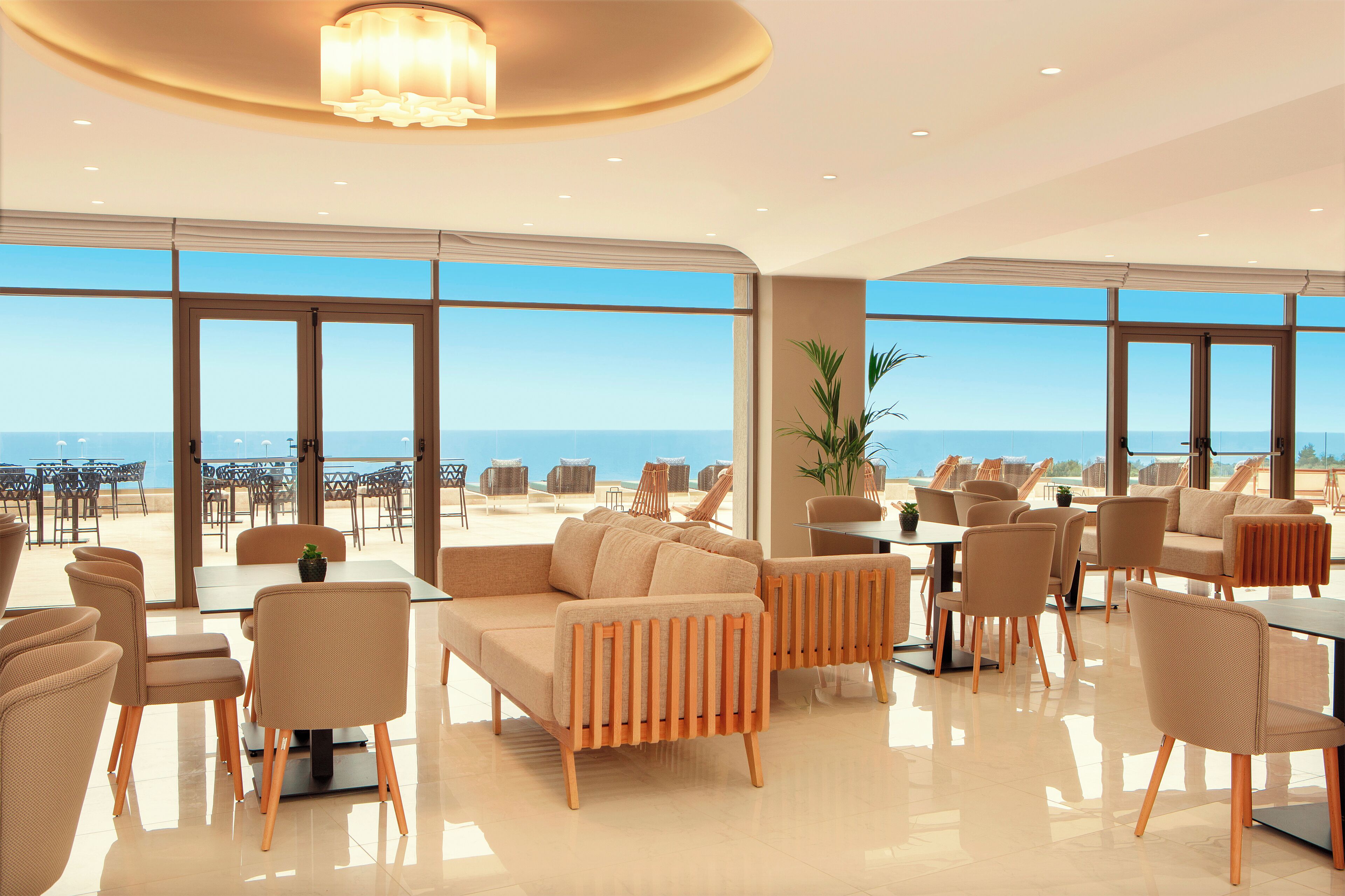 Amplio espacio interior con una gran disposición de asientos, una mesa central y vistas al océano a través de amplias ventanas.