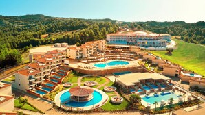 Un resort con varias piscinas, una piscina circular central y un edificio grande con balcones.