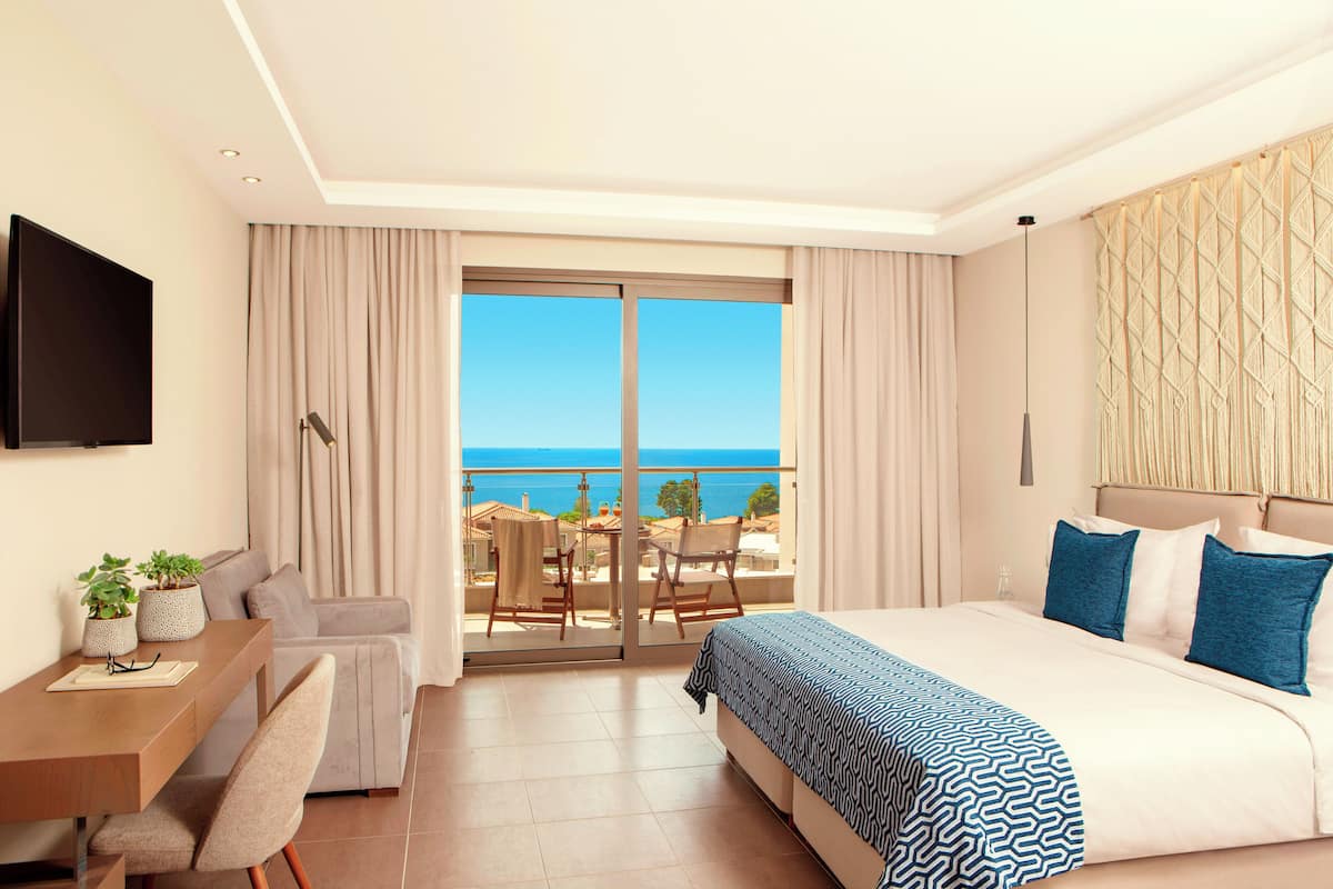 Habitación de hotel con cama, escritorio, silla y vista al mar.