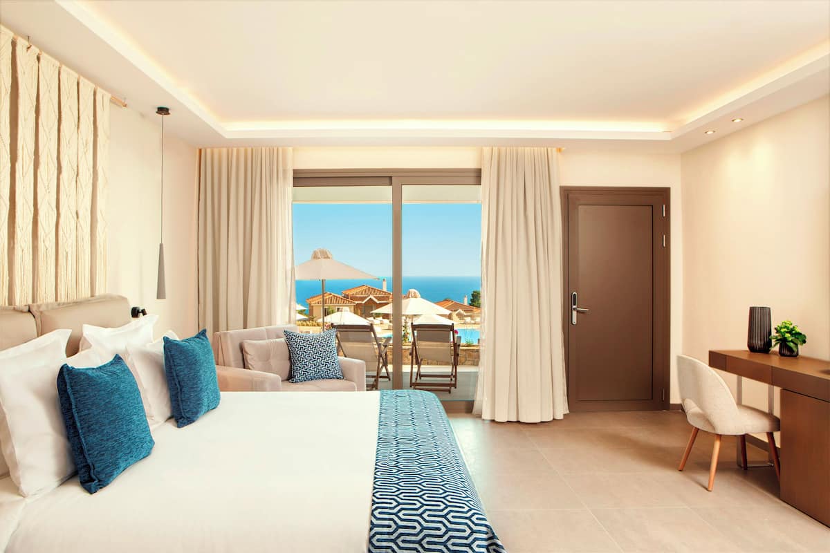 Habitación de hotel con una cama grande, un escritorio, una silla y vista al océano.