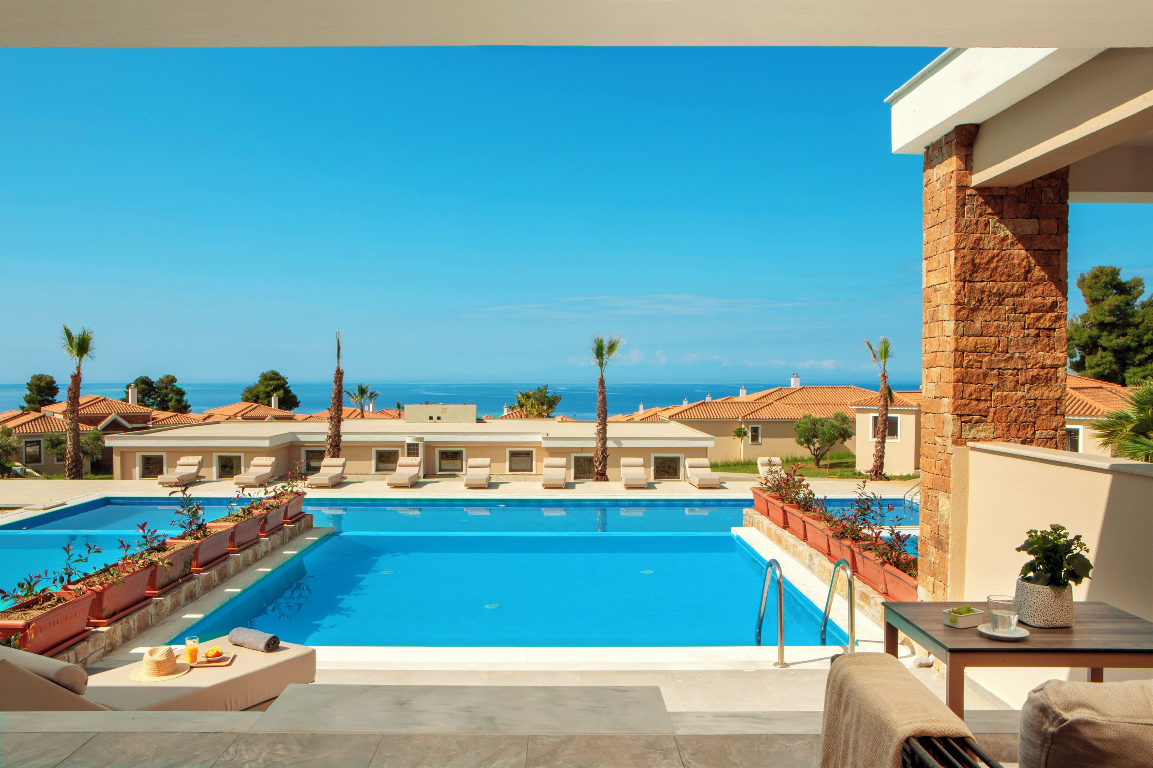 A swimming pool with lounge chairs and a view of the sea.