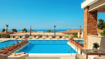 A swimming pool with lounge chairs and a view of the sea.