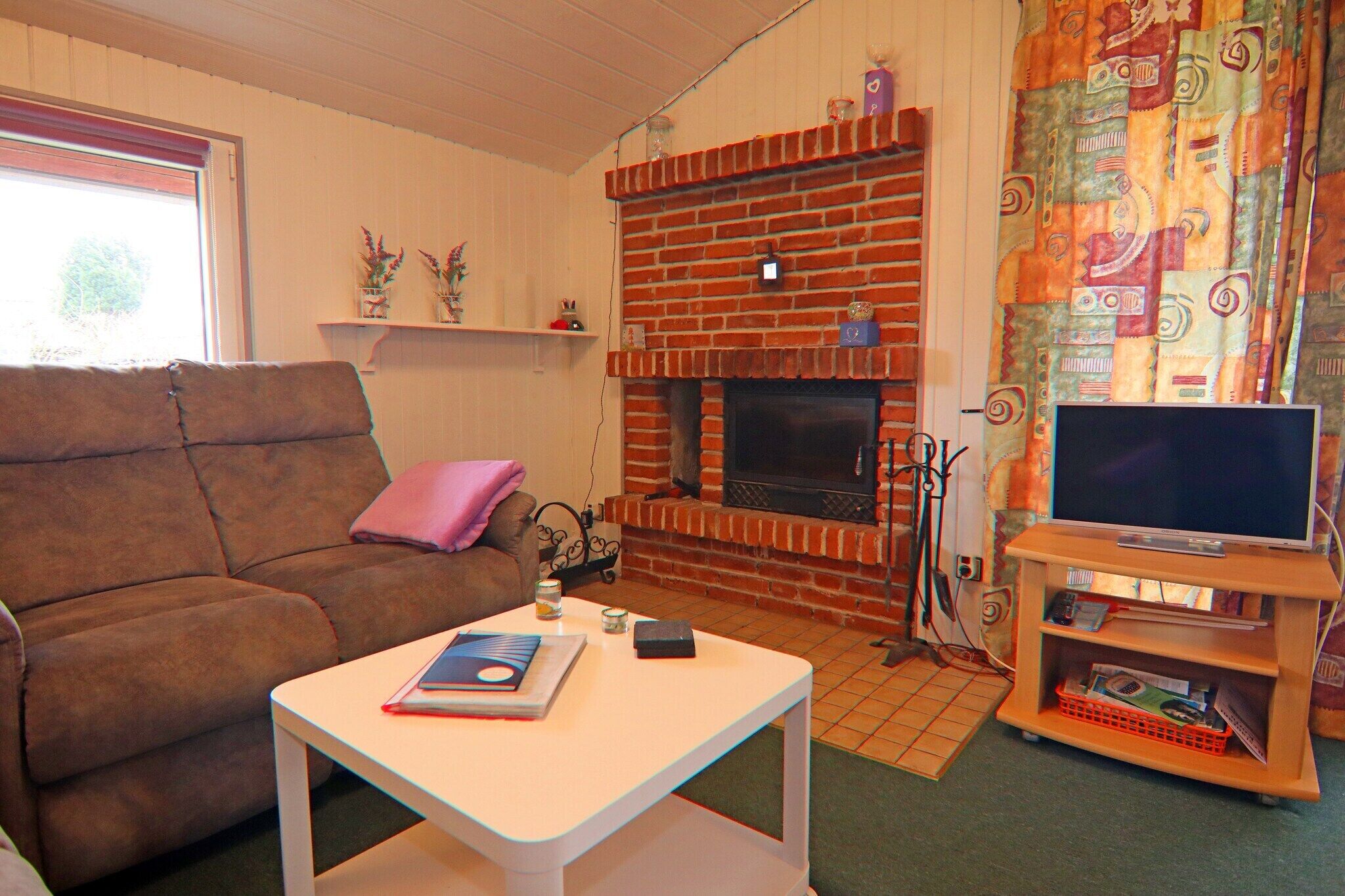 A living room with a brown sofa, a white coffee table, a fireplace, and a television on a wooden stand.