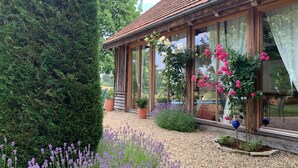 A wooden house with large windows, a gravel garden, and various potted plants. - Chalet in Styria with Pool & Panoramic Views (Fehring)