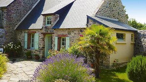 A stone building with a sloped roof, a small garden with lavender, and a stone pathway. - Stone House in Plurien near Sandy Beaches (Plurien)