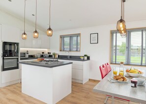 A modern kitchen with a central island, built-in appliances, and pendant lighting.