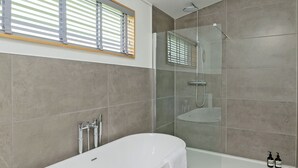 Ein modernes Badezimmer mit Badewanne, Dusche und einer Glaskabine für die Dusche.