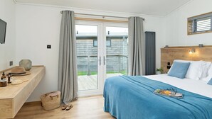 Ein Schlafzimmer mit Bett, Nachttisch, Fernseher und Blick ins Freie.