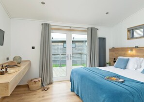 A bedroom with a bed, a bedside table, a TV, and a view of the outside.