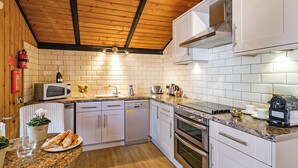 Une cuisine moderne avec des armoires blanches, un plafond en bois et un pare-feu en carreaux.