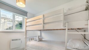 Ett rum med en våningssäng, ett fönster, ett element och en hängande lampa.