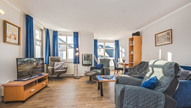 Sala de estar com televisão, sofá, poltrona e móvel de entretenimento em madeira.