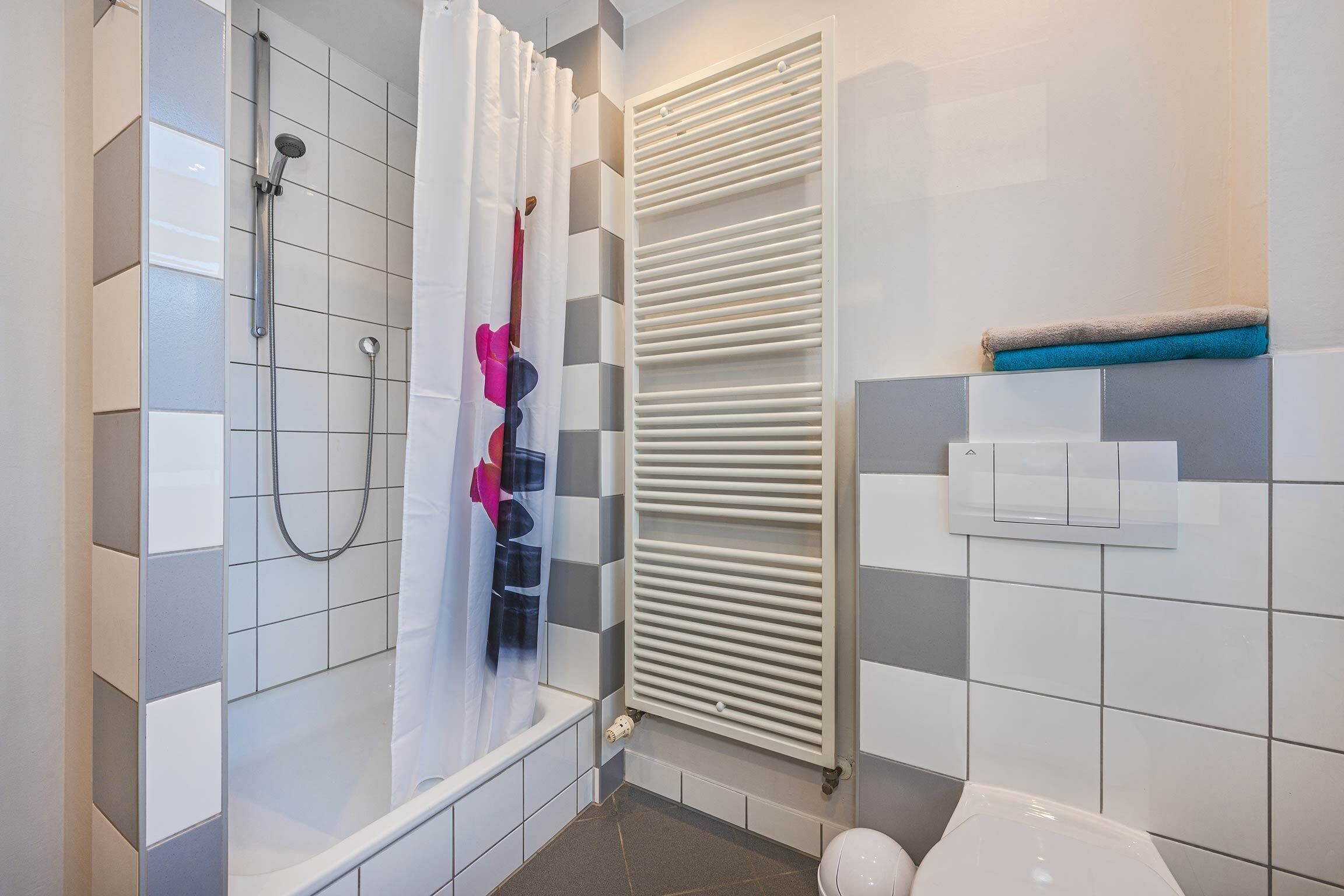 A bathroom with a shower, toilet, and towel rack.