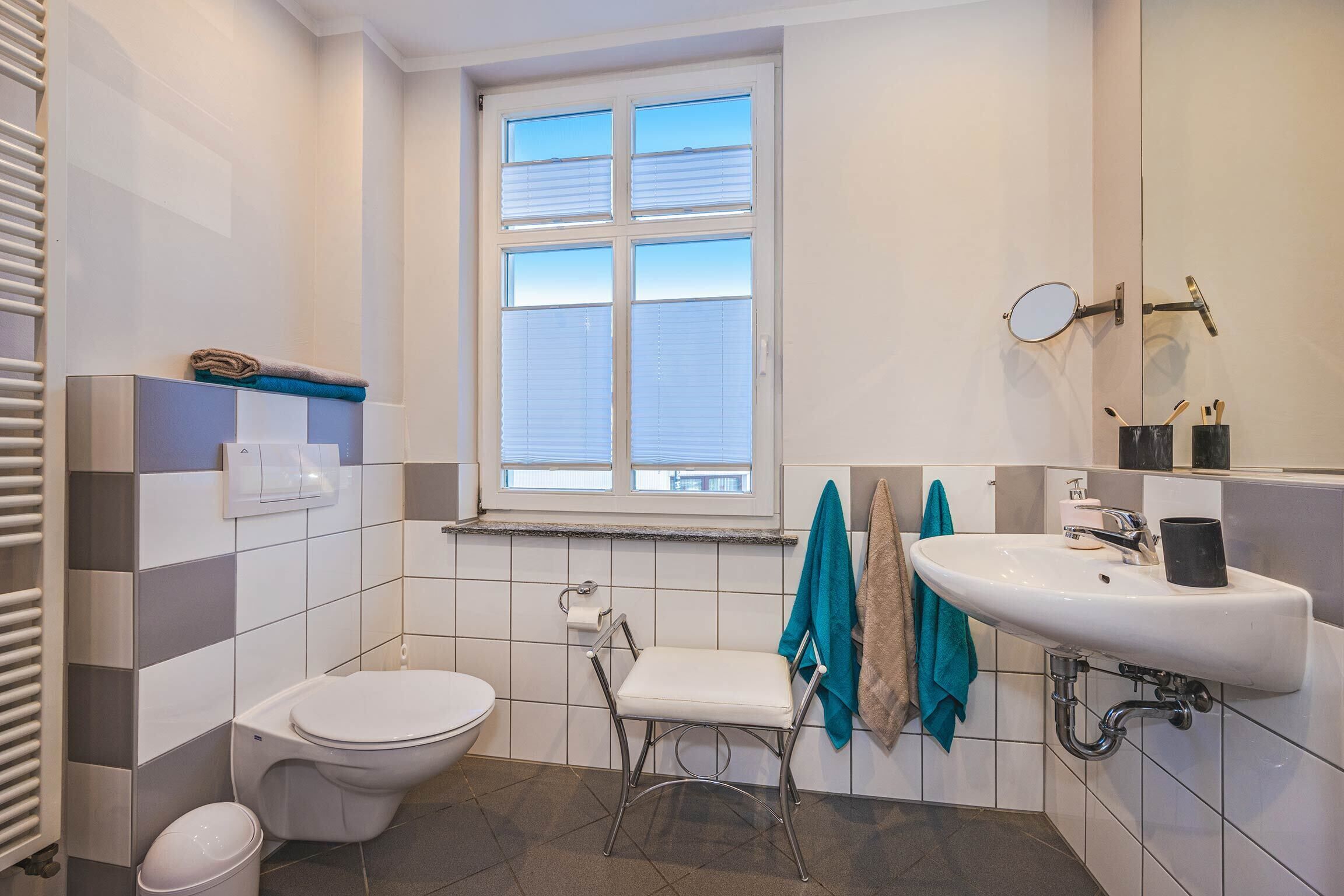 Ein Badezimmer mit Toilette, Waschbecken, Spiegel und Fenster.