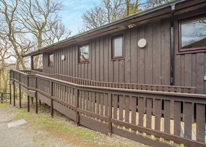 A wooden building with a wooden deck and a staircase leading to a door.