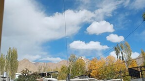 A mountain landscape with a clear sky and autumn-colored trees. - Munna Palace  (Leh)