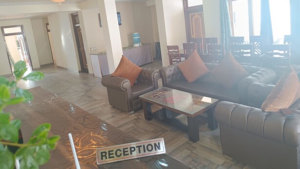 A spacious reception area with a chandelier, leather sofas, a coffee table, and a reception desk. - Munna Palace  (Leh)