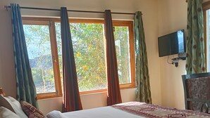 A bedroom with two beds, a TV on the wall, and a window with curtains. - Munna Palace  (Leh)
