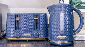 Due elettrodomestici blu con motivo a diamante, un bollitore e una borsa sullo sfondo.
