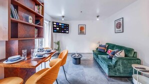 Un soggiorno moderno con zona pranzo, un divano verde e una TV a parete.