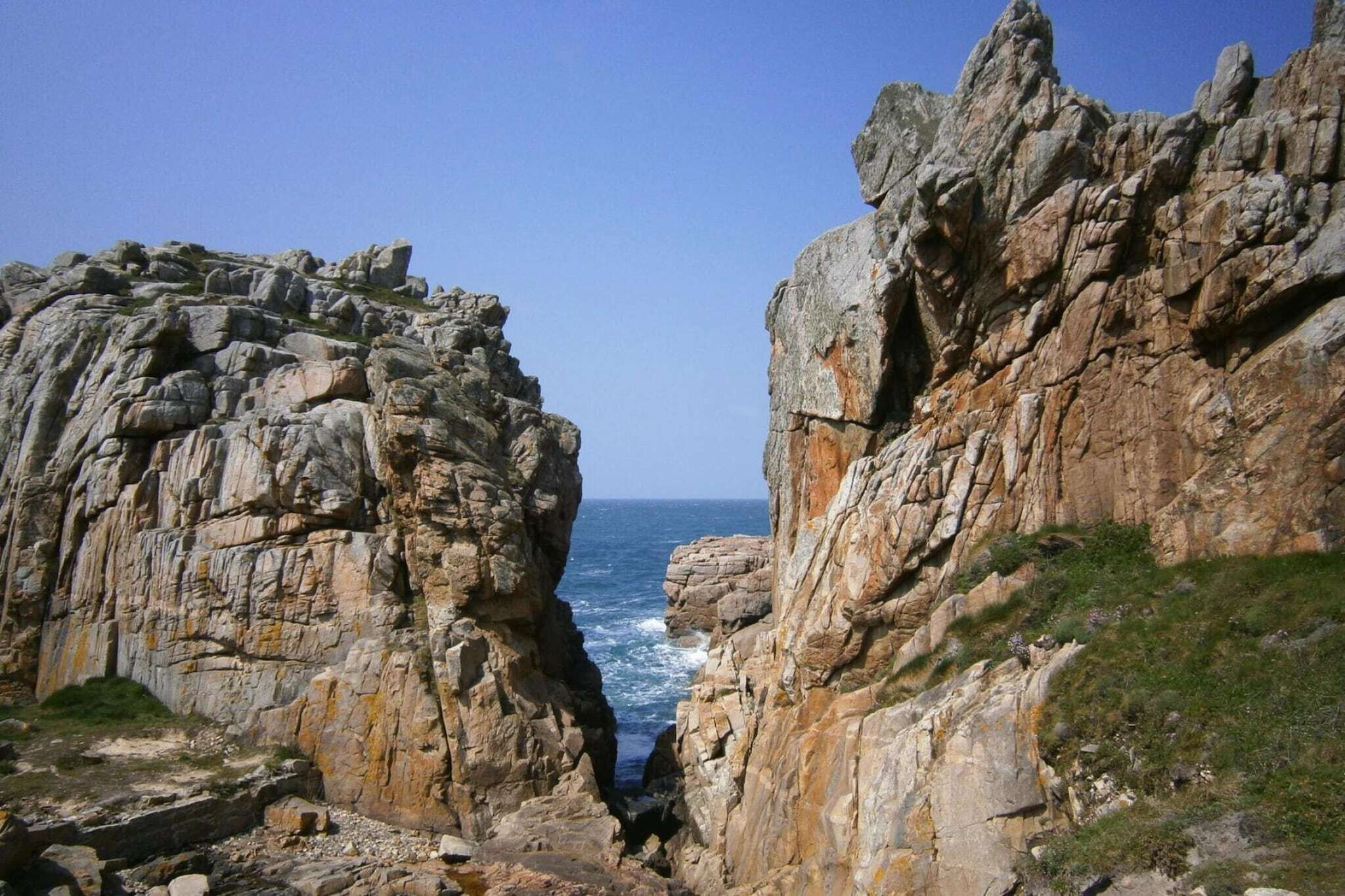 Paisagem costeira acidentada com falésias rochosas e vista para o mar.