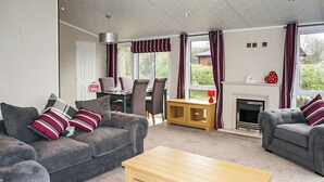 Ein Wohnzimmer mit grauen Sofas, einem Holztisch, einem Kamin und einem Essbereich mit Stühlen und Tisch.