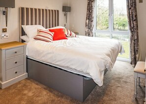 Une chambre à coucher avec un lit, des tables de chevet, une lampe et une fenêtre avec des rideaux.