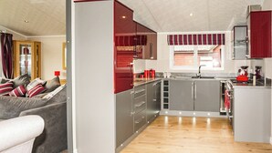 Eine moderne Küche mit grauen Schränken, einem fensterüberziehenden Vorhang in Rot und Weiß gestreift sowie einem Holzboden.