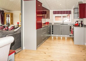 A modern kitchen with grey cabinets, a red and white striped window valance, and a wooden floor. - 3 bedroom accommodation in Carnforth (Carnforth)