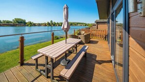 Eine Holzterrasse mit Tisch und Bänken mit Blick auf einen See.