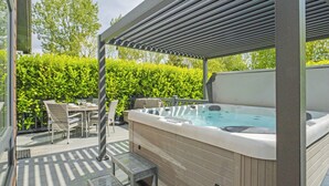 A hot tub under a pergola, surrounded by a wooden deck and outdoor furniture. - 2 bedroom accommodation in Skirlaugh, Nr Hull (Skirlaugh, Nr Hull)