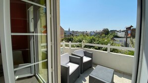 En balkon med fletmøbler og udsigt over byen.