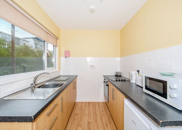 A compact kitchen with a sink, stove, microwave, and cabinets.