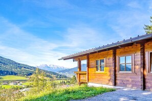 Una baita di legno con un balcone, con le montagne sullo sfondo.