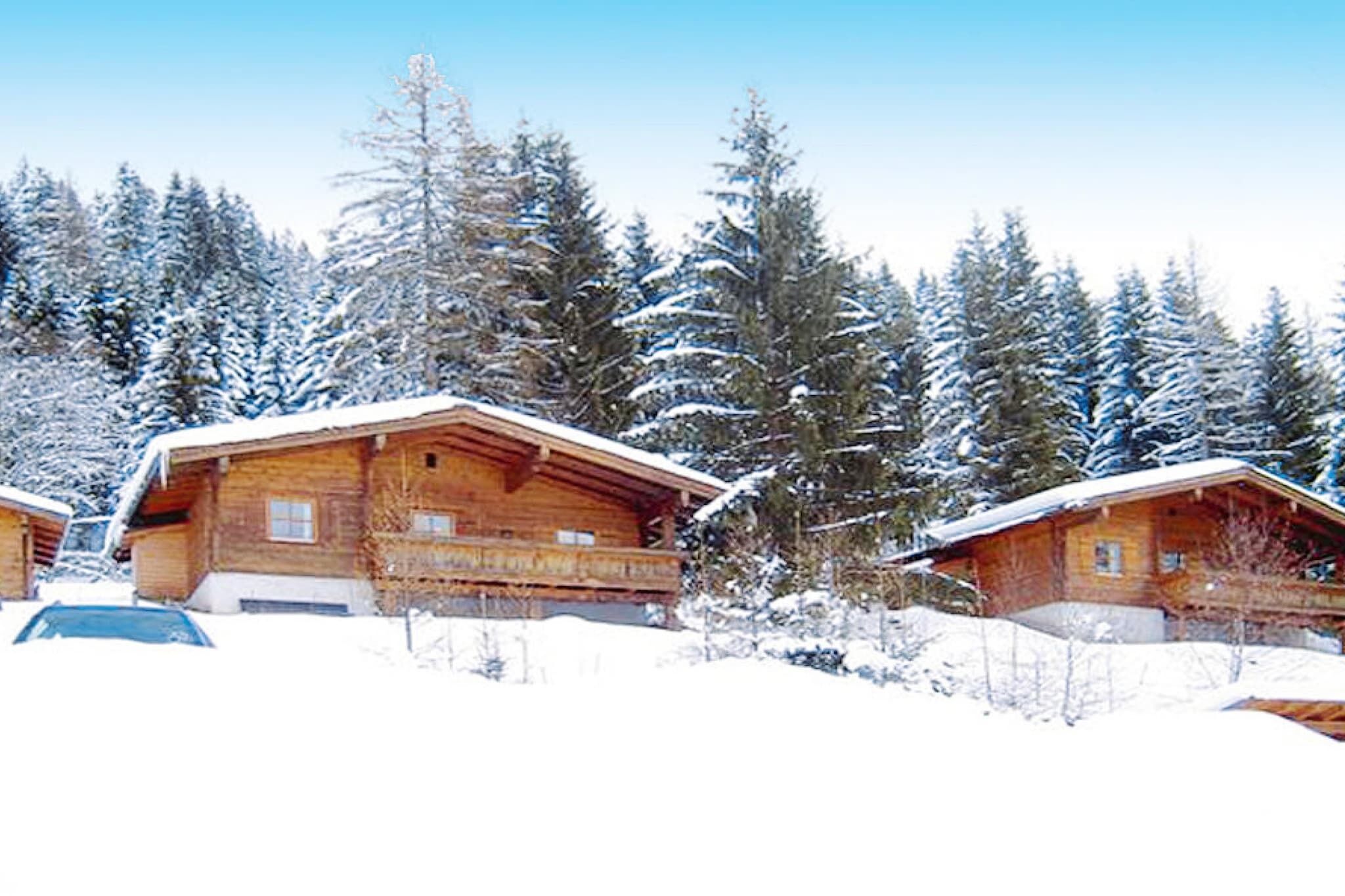 A wooden cabin with a balcony, surrounded by snow-covered trees.