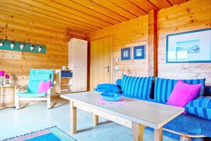 A wooden cabin interior with a sofa, a chair, a table, and wall-mounted decorations.