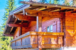 Eine Holzhütte mit Balkon, großen Fenstern und einem geneigten Dach.