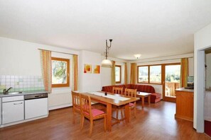 Cozy living space with a dining area and kitchenette, featuring a wooden dining table and bench.