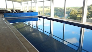 En indendørs swimmingpool med udsigt over landskabet.