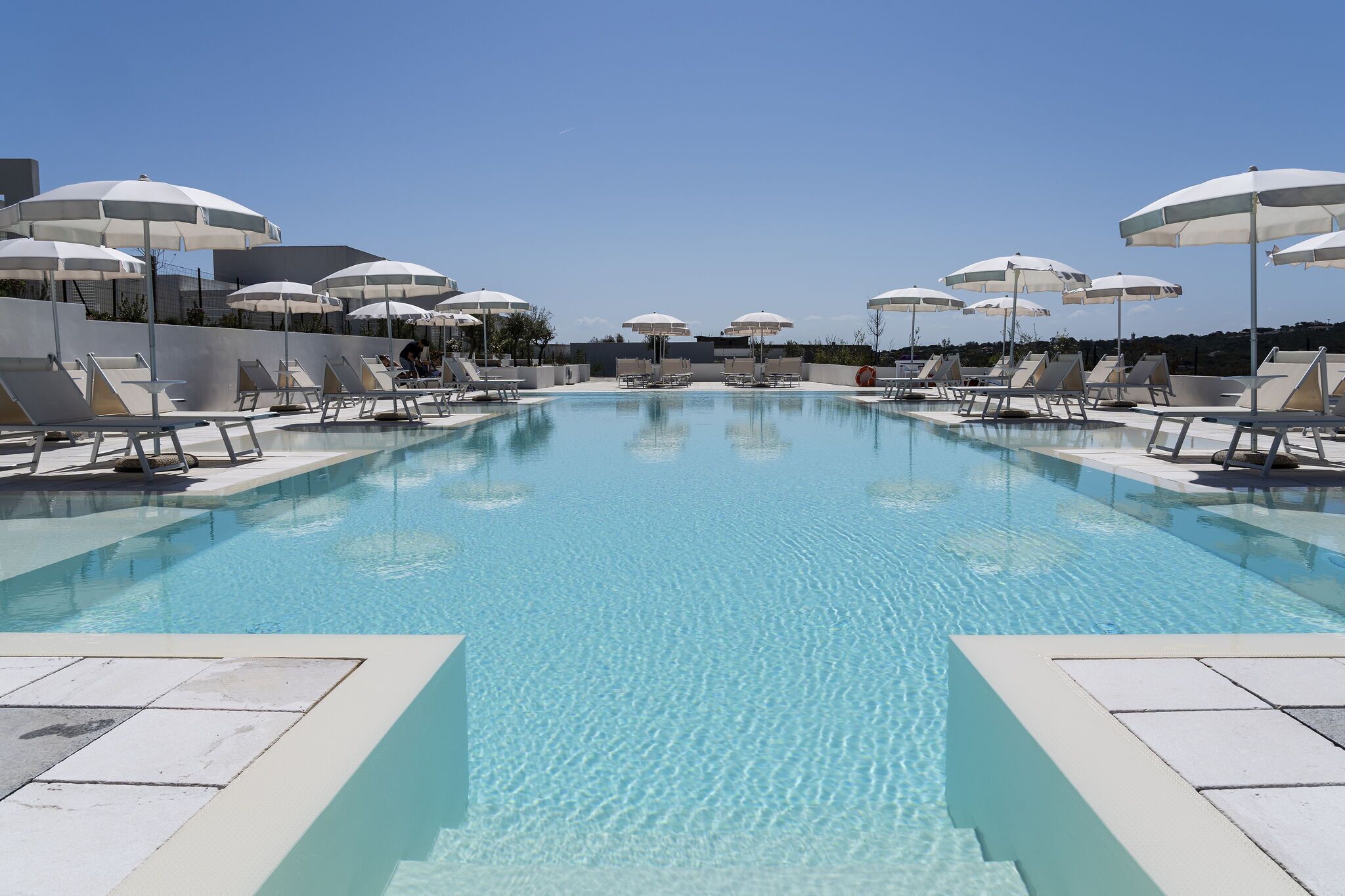 A swimming pool with sun umbrellas and lounge chairs.