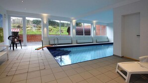 A swimming pool with a bench, a chair, and a small table. - Appartement in Westerland auf Sylt (Westerland)