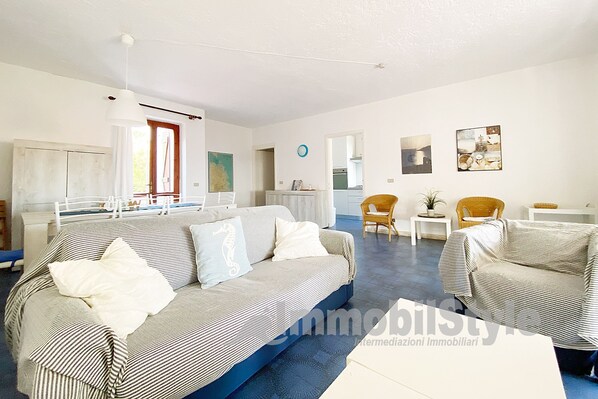 A living room with a striped sofa, two armchairs, a coffee table, and a dining area with a table and chairs.