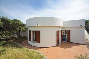 A modern, circular building with a flat roof and a covered patio area.