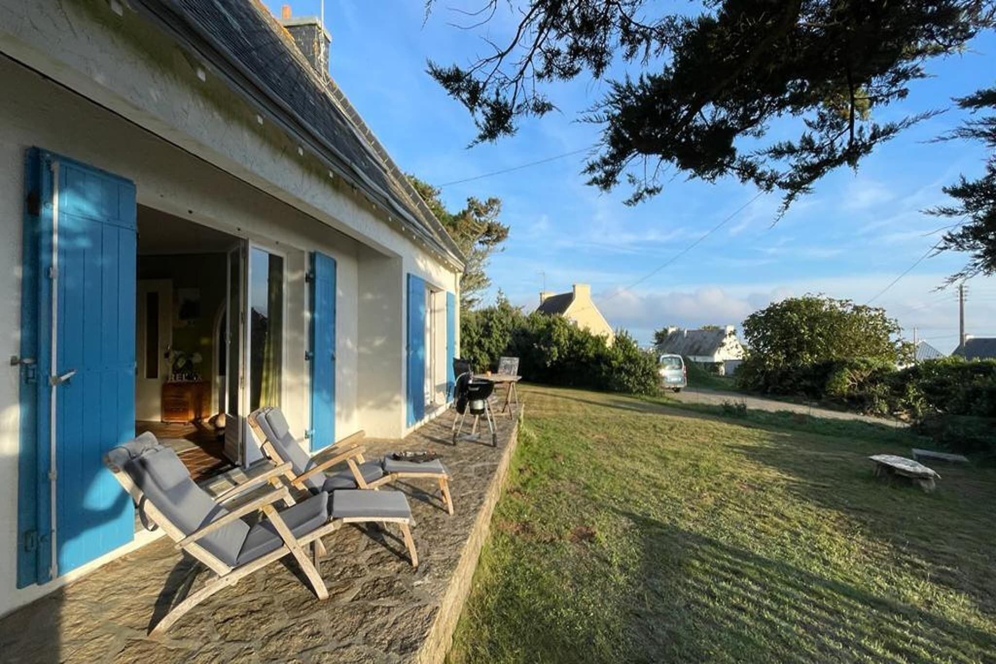 A house with a covered porch, outdoor seating, and a lawn.