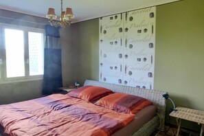 Una camera da letto con un letto, un comodino, una lampada, una parete decorata a tema cioccolato e una finestra con tende.